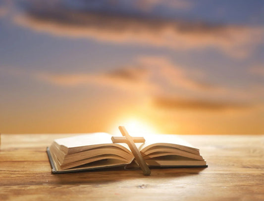 Open Bible with a cross necklace symbolizing God's strength and encouragement during difficult times.