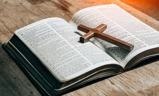 Cross necklace placed on an open Bible representing the meaning of Christianity, faith, and God's love.
