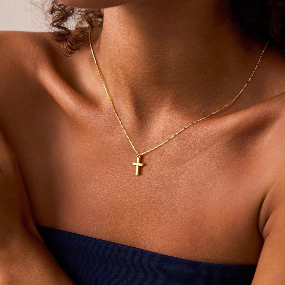 Woman wearing a minimalist gold Christian cross necklace for everyday faith