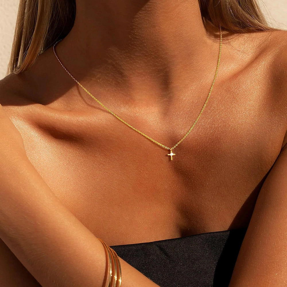 Woman wearing a minimalist gold Christian cross necklace for everyday faith